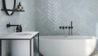bathroom-renovation-freestanding-white-oval-bath-light-mint-green-gloss-rectangular-tiles-herringbone-pattern-pebble-look-floor-tiles-black-taps-&-wall-mirror-round
